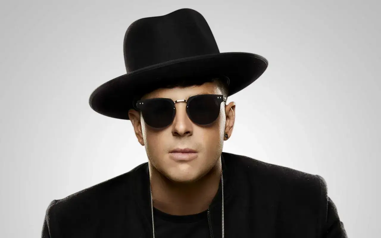 Timmy Trumpet w czarnym kapeluszu i okularach przeciwsłonecznych, gotowy na koncert w Polsce.