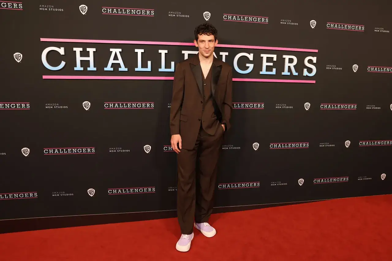 Josh O'Connor steht auf dem roten Teppich vor einem Banner mit der Aufschrift
