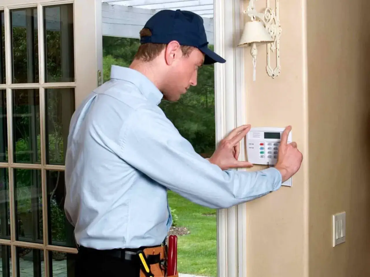 Un homme installe un panneau de contrôle d'alarme à domicile. C'est une solution d'alarme à installer soi même pour plus de sécurité.