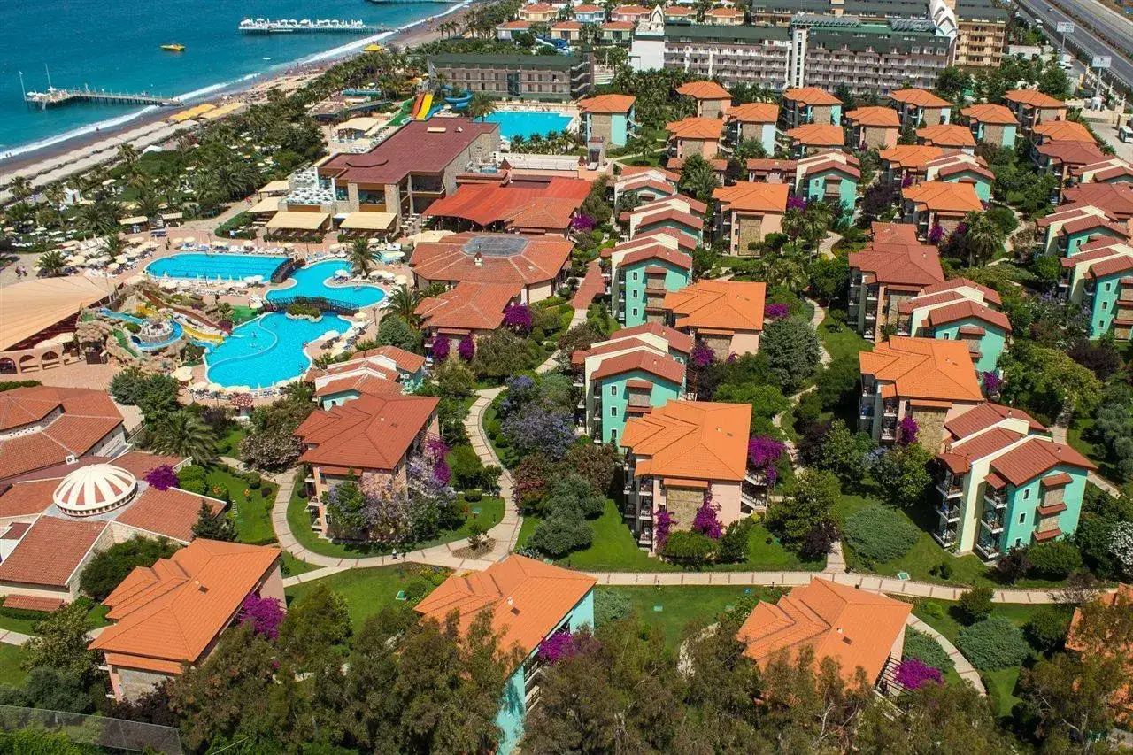 Widok z lotu ptaka na Gypsophila Holiday Village: kolorowe budynki, baseny i plaża.