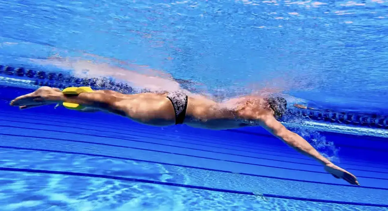 Swimmer using a pull buoy between legs to focus on upper body strength. This demonstrates how to use a pull buoy for training.