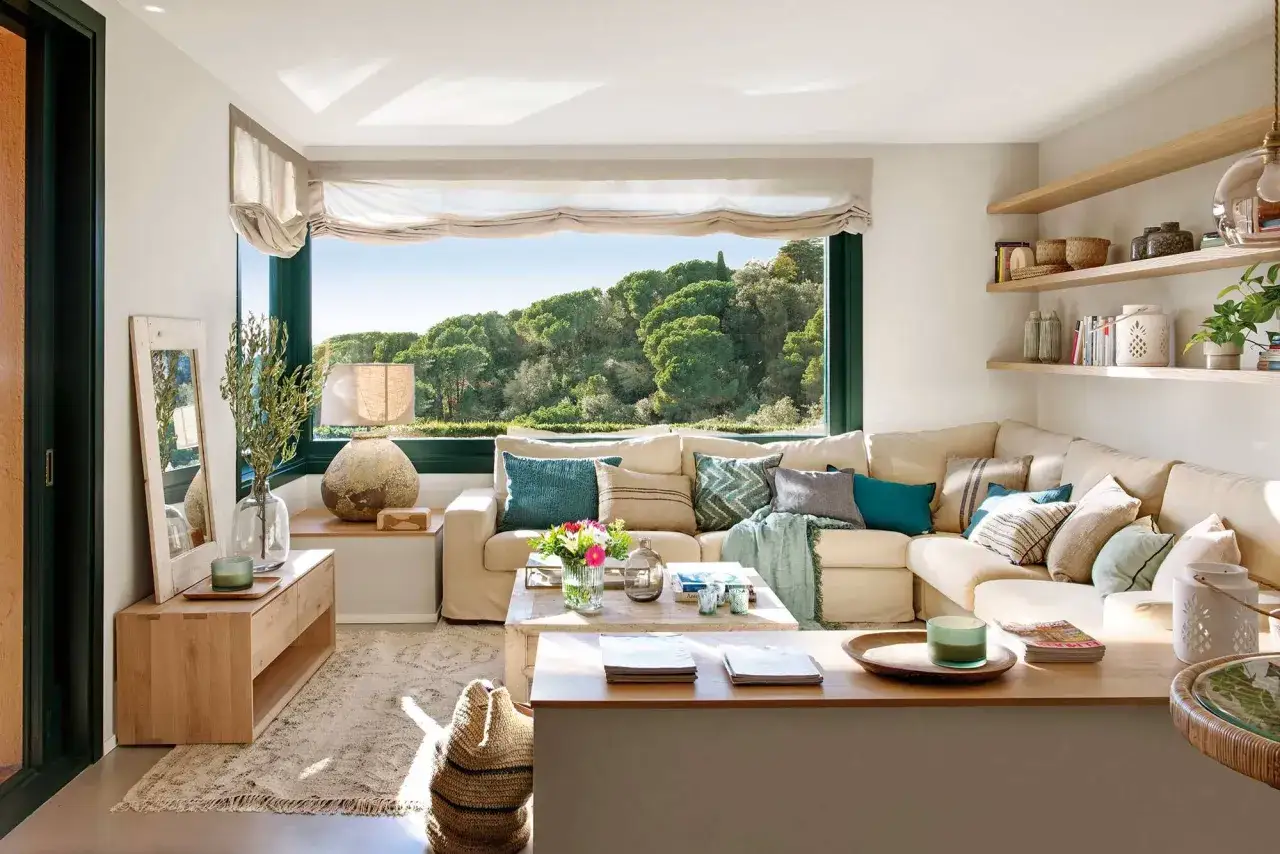 Un sal&oacute;n acogedor con sof&aacute; modular, mesa de centro de madera y gran ventanal. Ideas para como iluminar un salon con luz natural y artificial.
