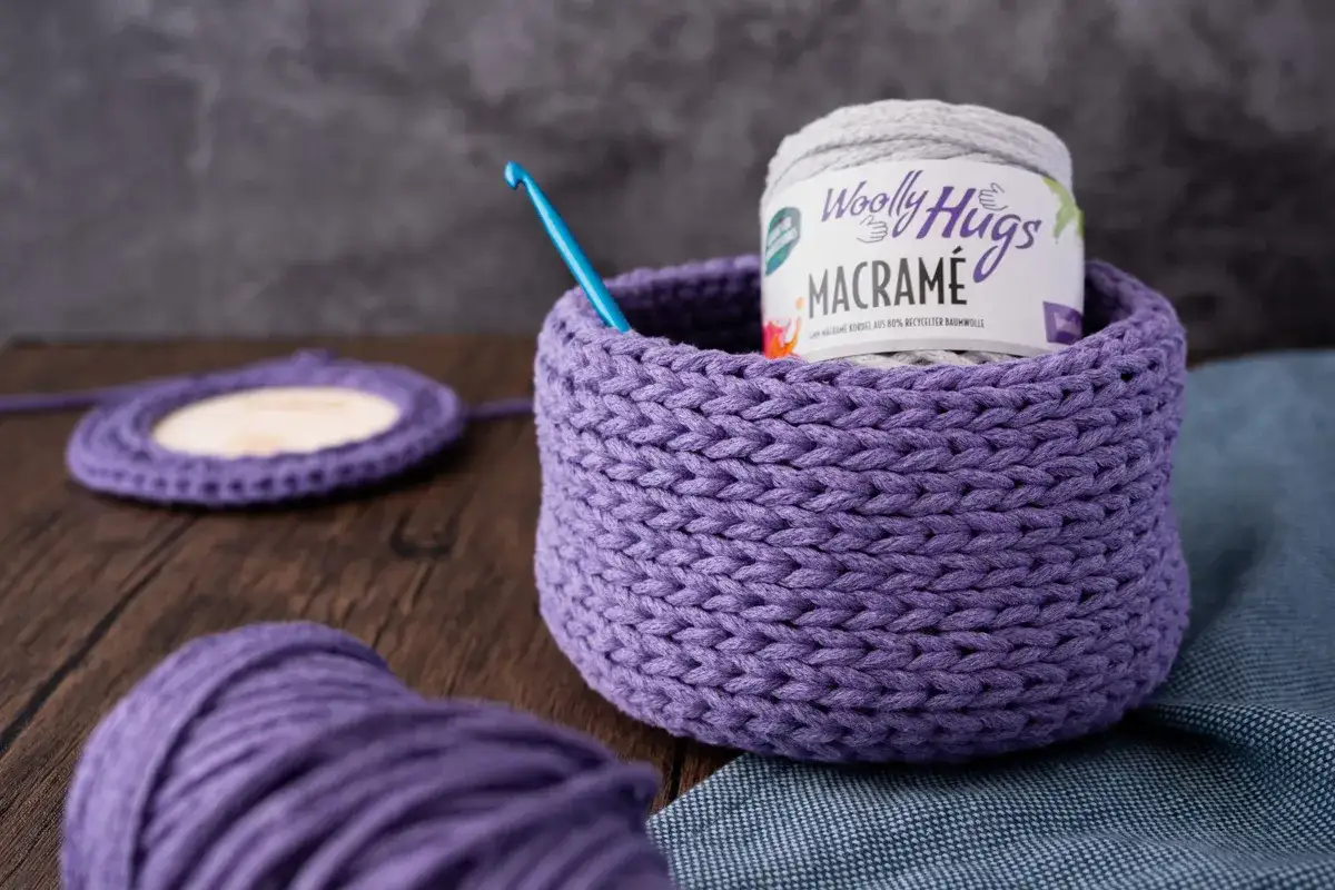 Ein lila geh&auml;kelter Korb mit Garnrolle und H&auml;kelnadel. Perfekt f&uuml;r eine makramee korb anleitung.