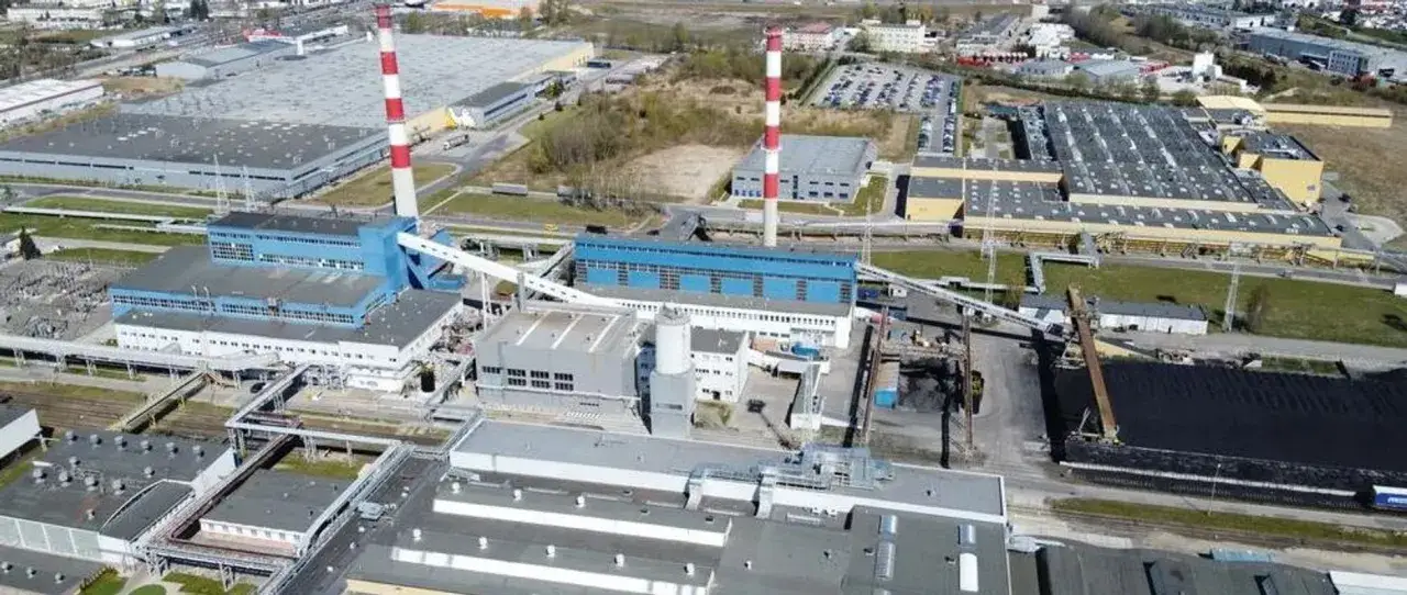Widok z lotu ptaka na kompleks przemysłowy, gdzie kormoran opony producent ma swoje zakłady. Widać kominy, hale produkcyjne i składy surowców.