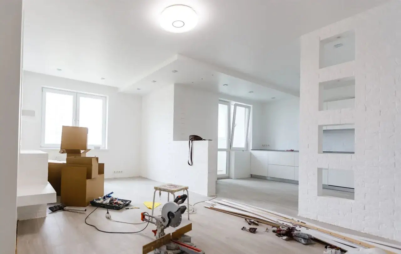 Interno in ristrutturazione con scatole, attrezzi e **lastre di cartongesso** pronte per essere installate.