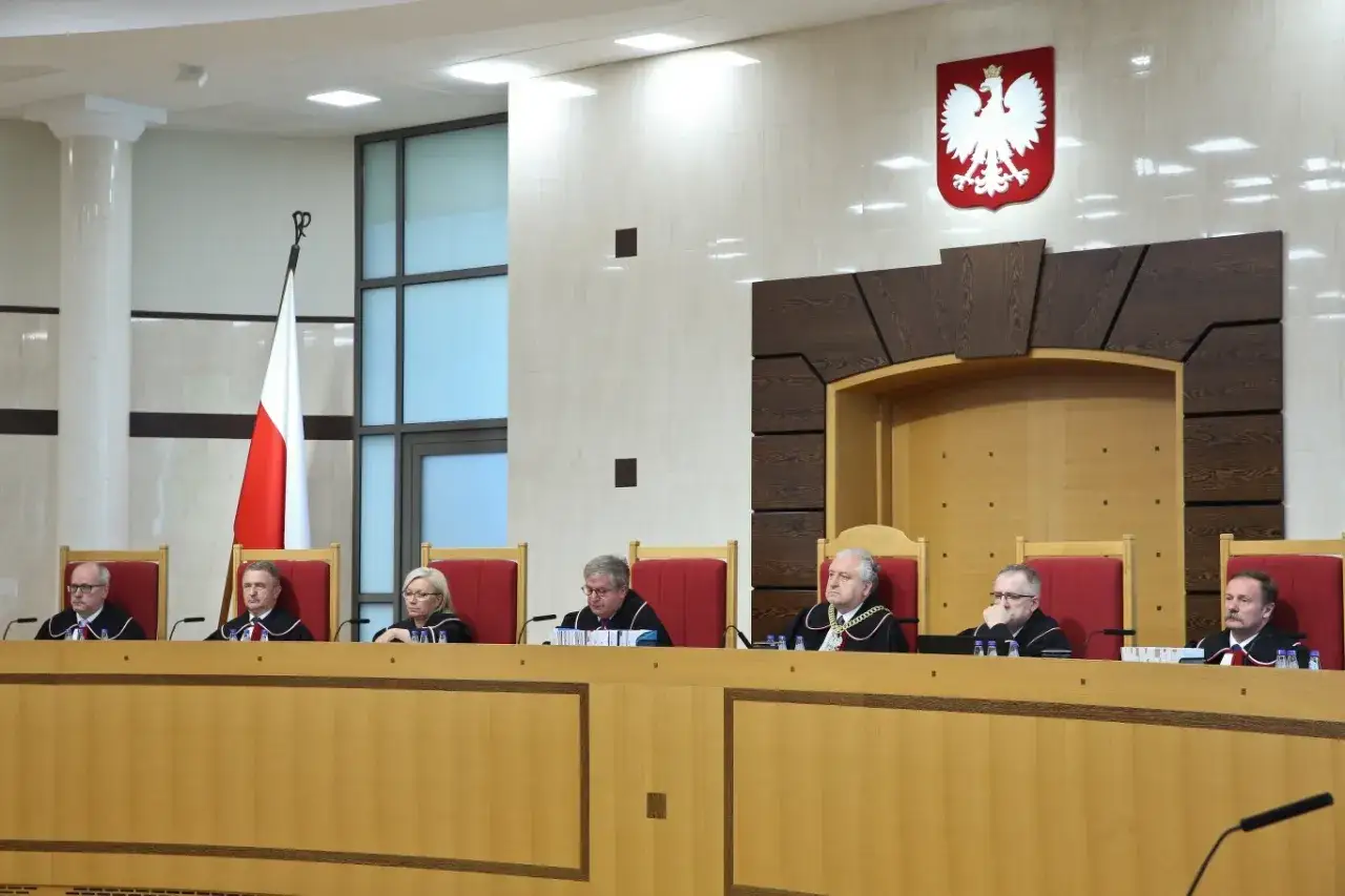 Siedmiu sędziów w togach zasiada w ławach. Na ścianie wisi godło Polski. To sala obrad trybunału stanu.