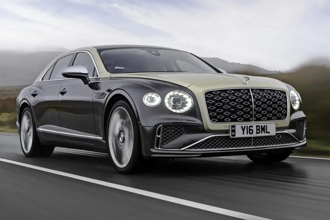 Elegancki Bentley Flying Spur w dwukolorowym malowaniu pędzi po drodze. Sprawdź aktualną bentley cena.