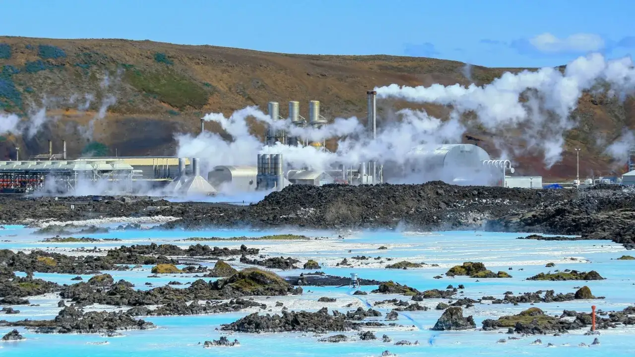 Geothermieanlage auf Island mit dampfenden Schornsteinen über blauem Wasser. Die Strompreise auf Island sind hier durch nachhaltige Energie beeinflusst.