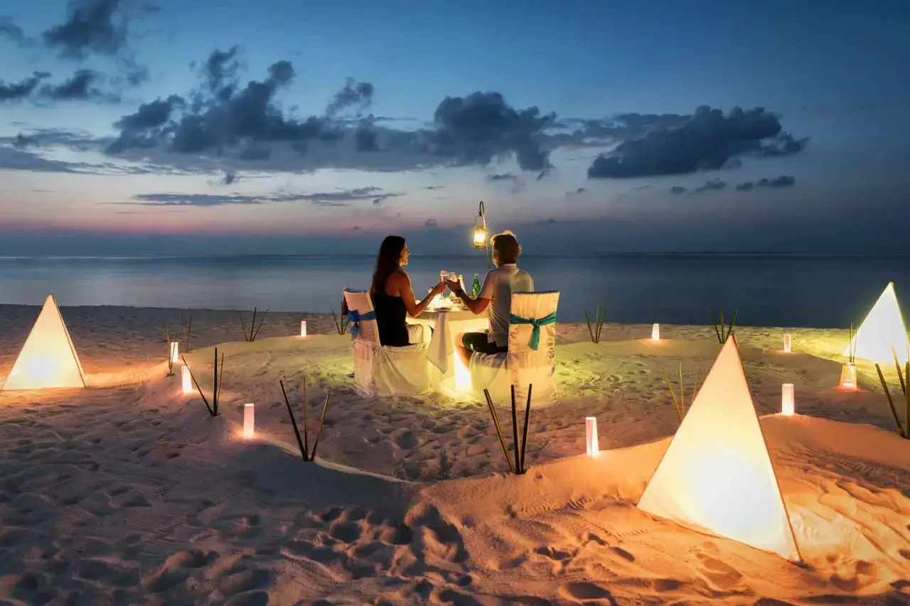 Romantyczna kolacja na plaży przy zachodzie słońca. Idealne miejsce na podr&oacute;ż poślubną, gdzie marzenia stają się rzeczywistością.