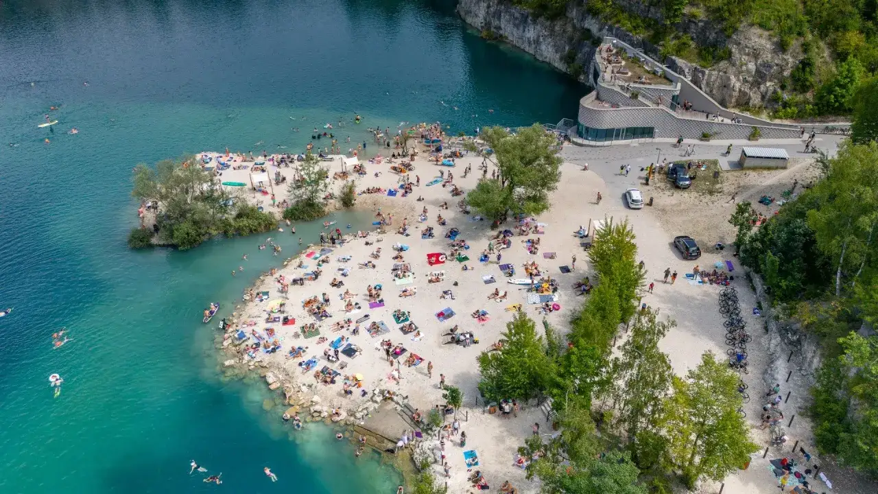 Tłum ludzi wypoczywa na plaży i kąpie się w turkusowej wodzie Zakrzówka w Krakowie.