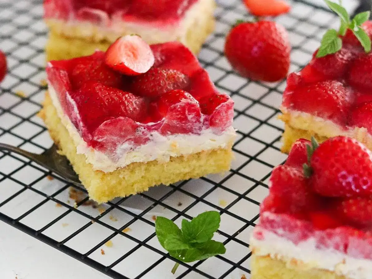 Saftiger Erdbeerkuchen vom Blech mit frischen Erdbeeren und Tortenguss, garniert mit Minze.