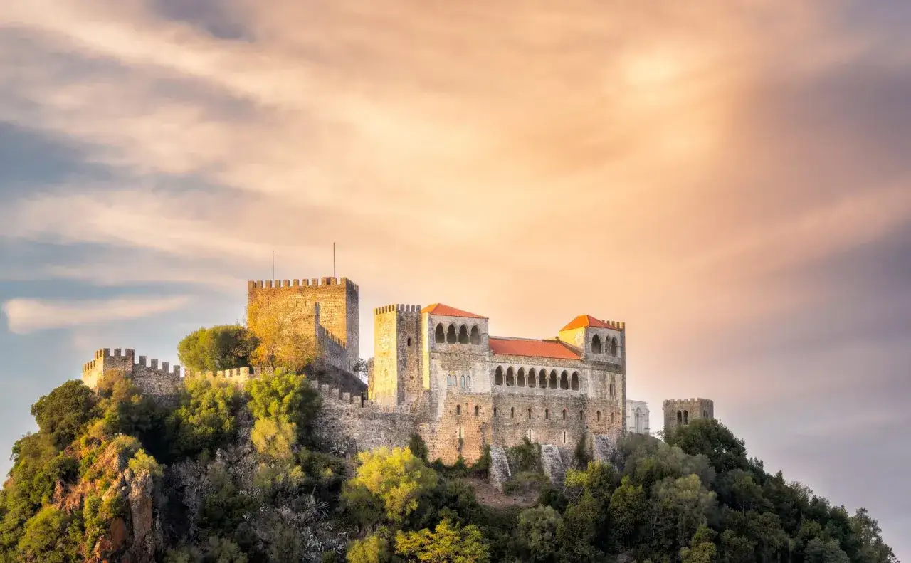 Majest&auml;tische Burg thront auf einem H&uuml;gel in Portugal, Leiria. Sonnenuntergang beleuchtet die alten Mauern und T&uuml;rme.
