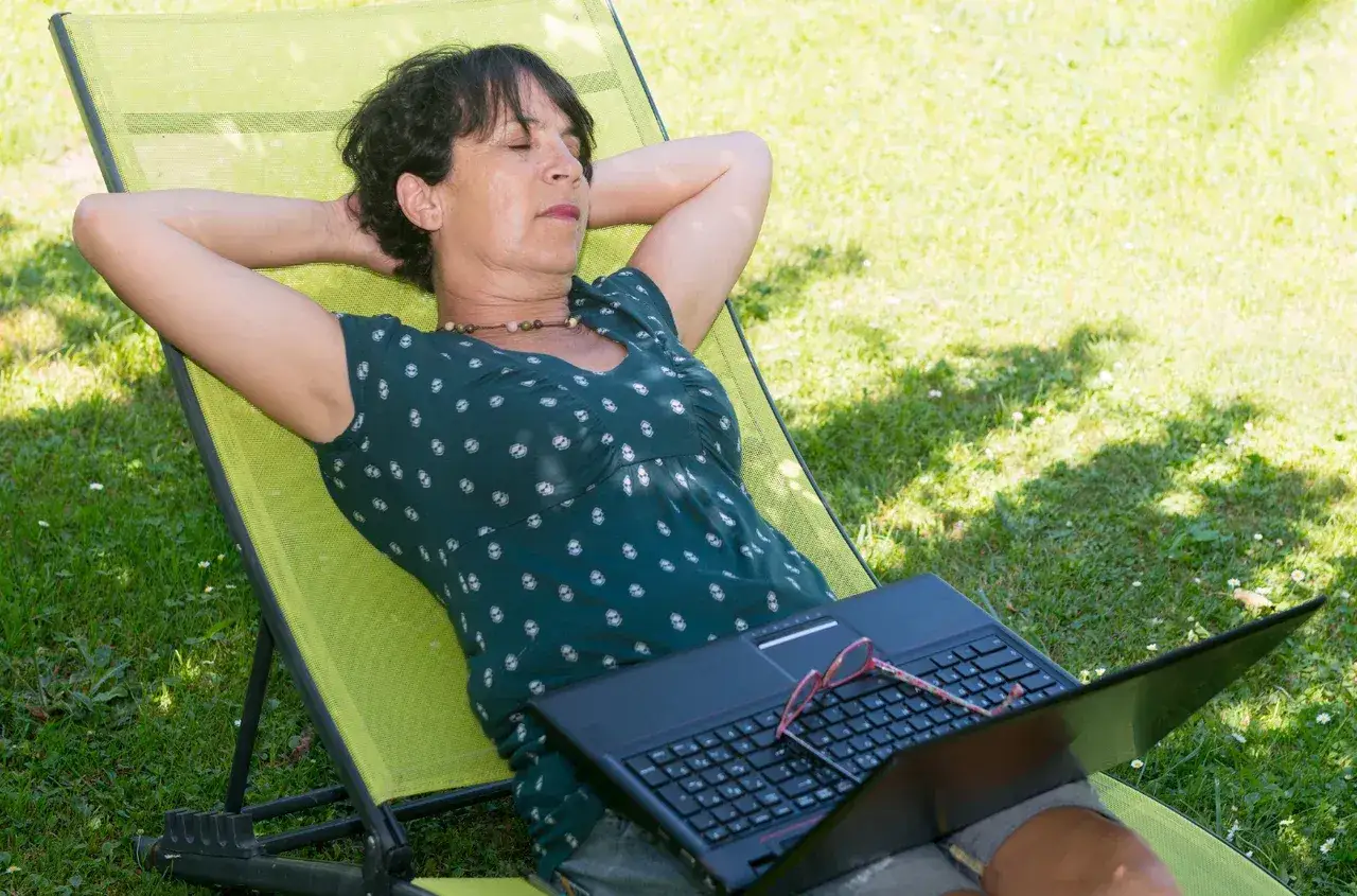 Kobieta odpoczywa na leżaku z laptopem, marząc o tym, ile dni urlopu przysługuje po studiach.
