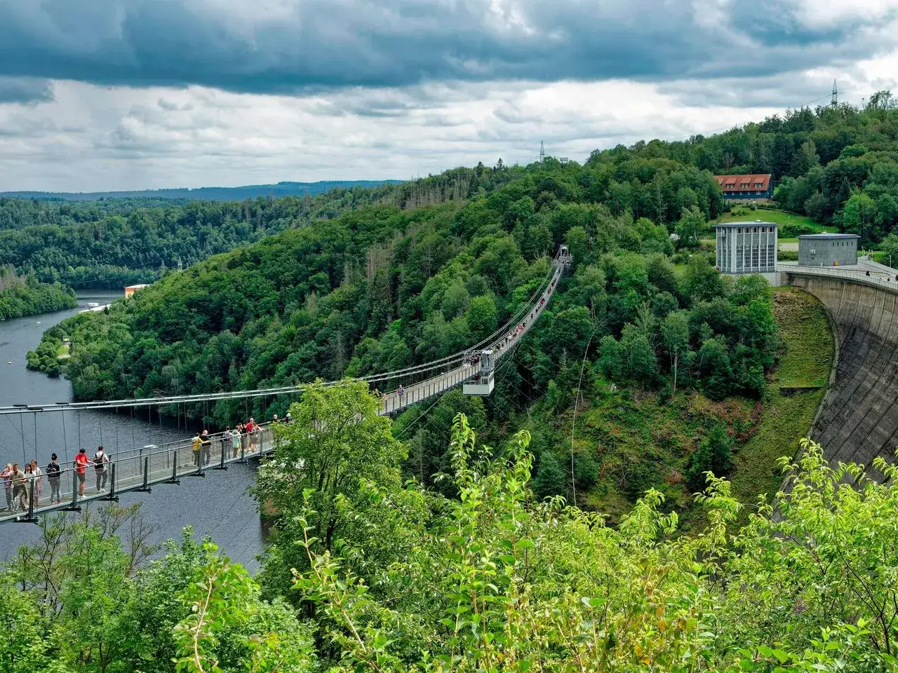 Hängebrücke über die Rappbodetalsperre im Harz. Besucher genießen die Aussicht auf die grüne Landschaft und das Wasser.