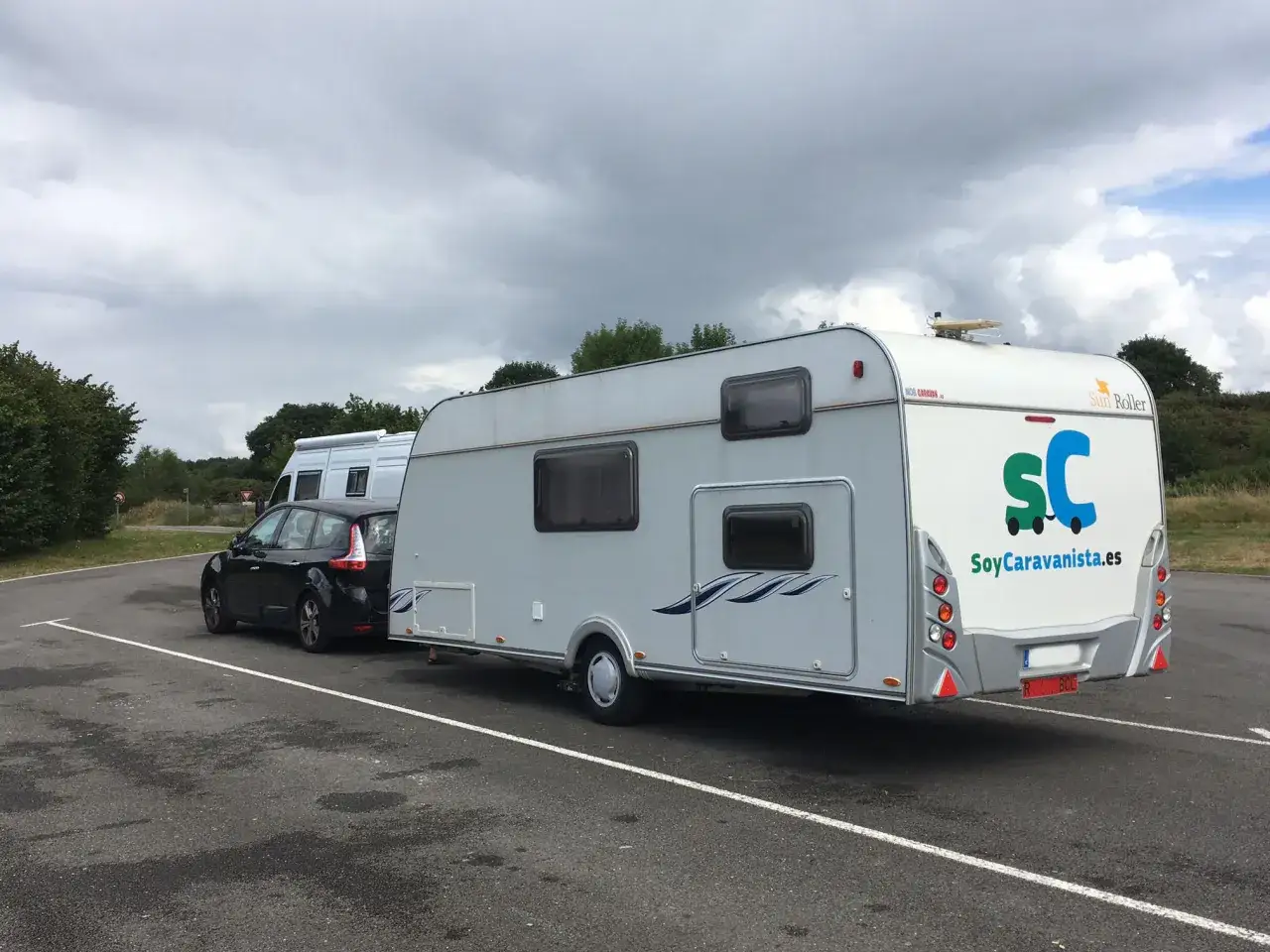 Coche negro y caravana gris aparcados. Un conjunto ideal que se puede conducir con el carnet B para tus escapadas.