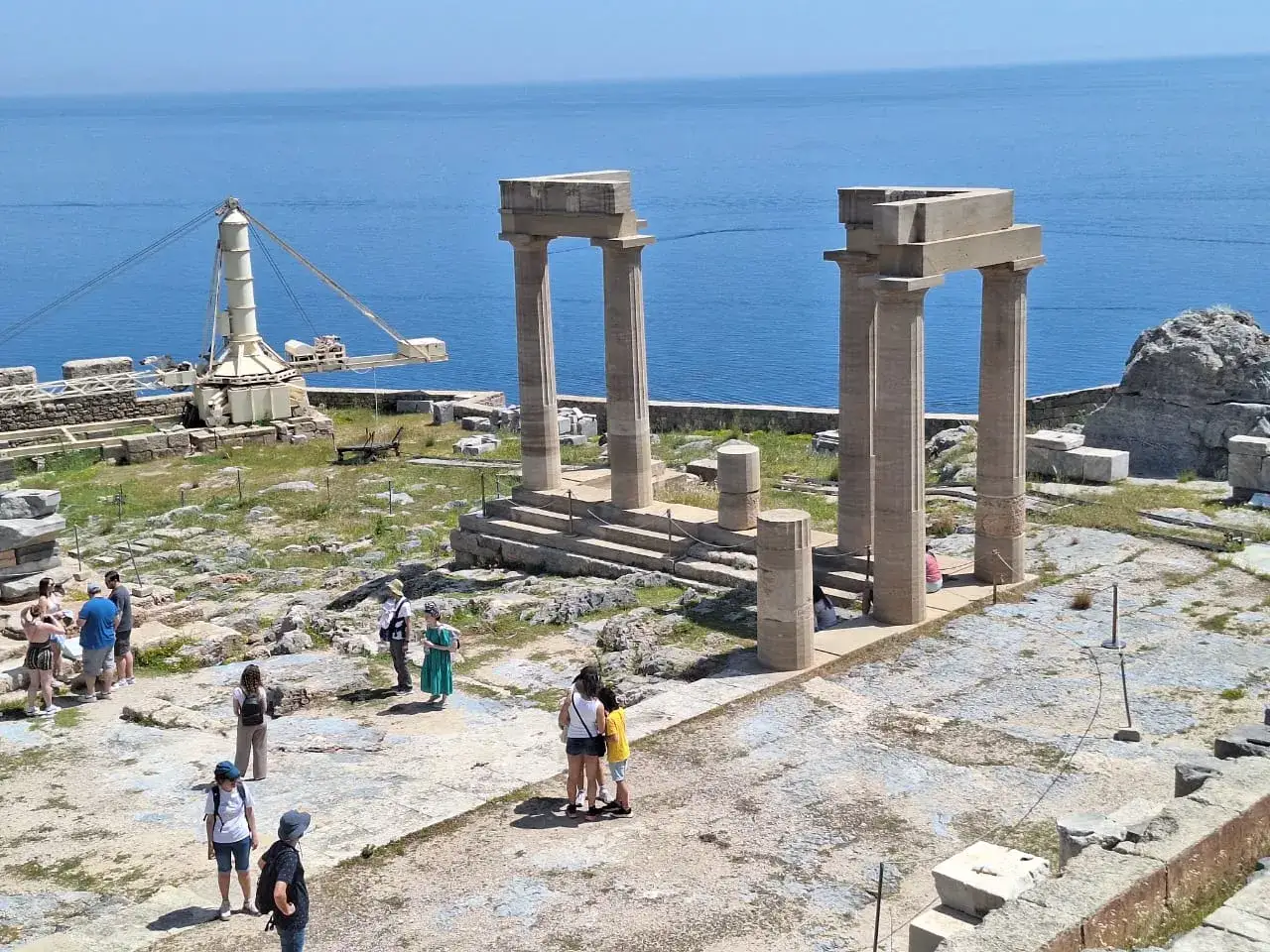 Ruiny Akropolu w Lindos, Rodos. Zwiedzający podziwiają starożytne kolumny i morze. To jedne z gł&oacute;wnych rodos atrakcje turystyczne.