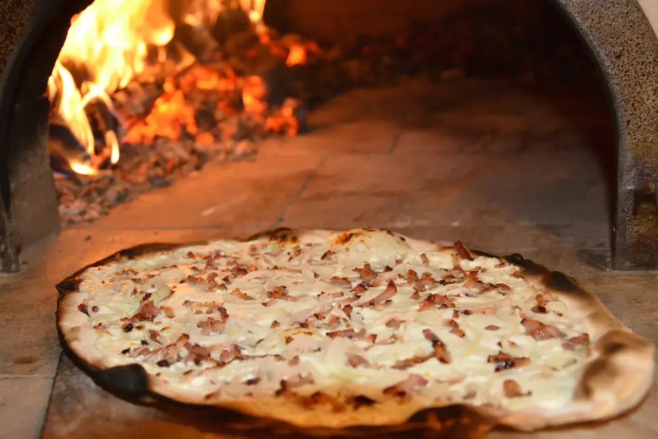 Tarte flambée, une spécialité dont l'origine remonte à l'Alsace, cuite au feu de bois.