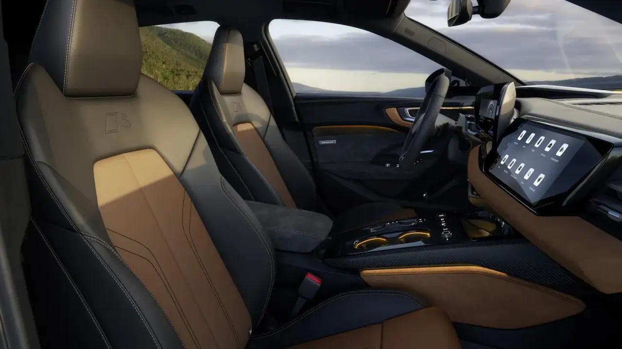 Wnętrze Audi A5 Avant 2025: sportowe fotele z alcantary i skóry, nowoczesny ekran multimedialny i widok na góry.