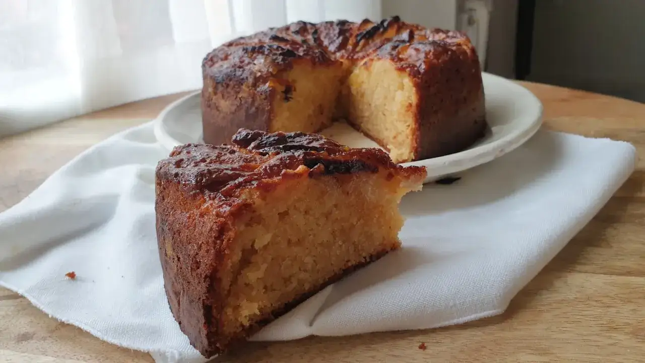 Un delicioso bizcocho de plátano y manzana, con una rebanada servida sobre una servilleta blanca.