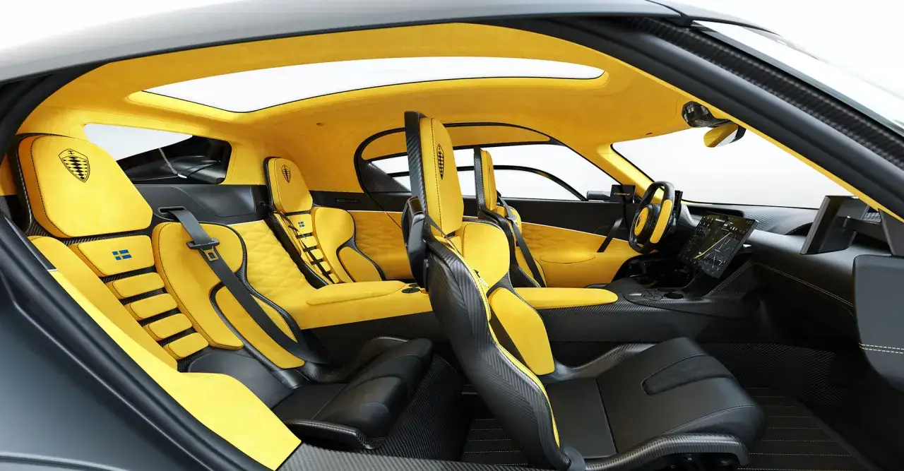 Innenraum des Koenigsegg Gemera: gelbe Ledersitze mit schwarzem Carbon, Sonnendach und schwedische Flagge.