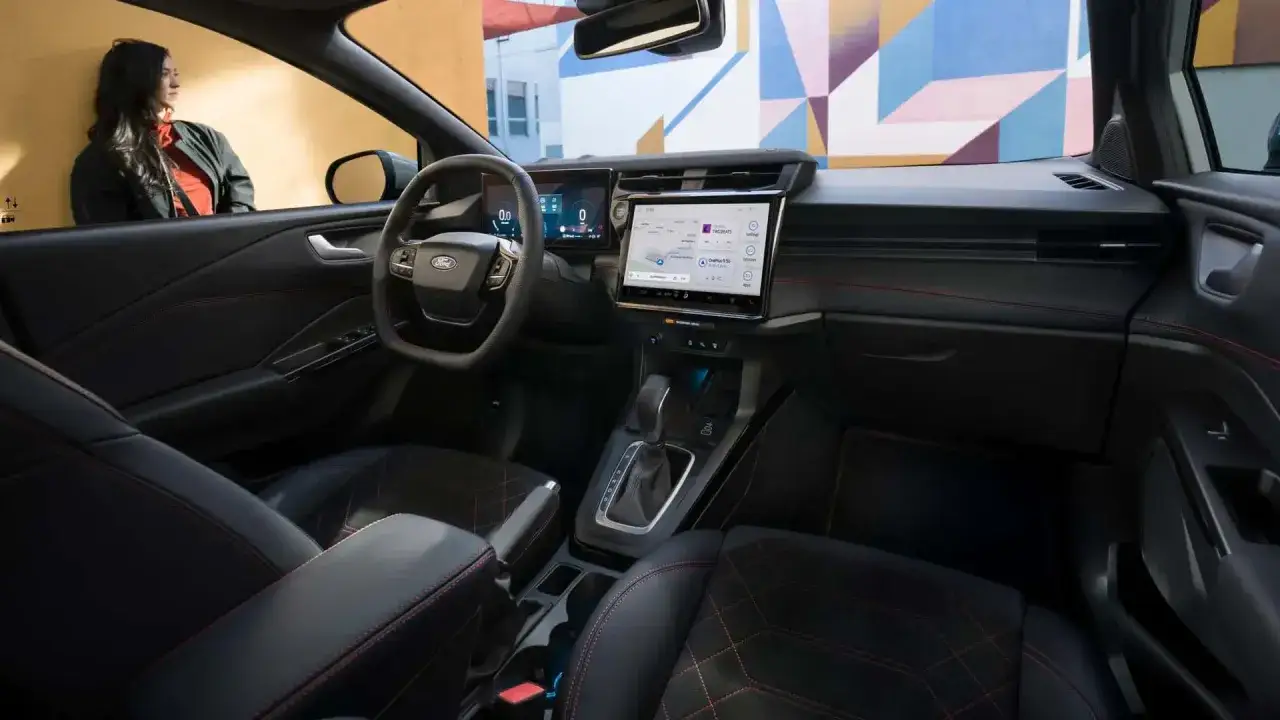 L'intérieur moderne du Ford Puma, avec ses sièges en cuir noir et surpiqûres rouges, son grand écran tactile et son tableau de bord numérique.