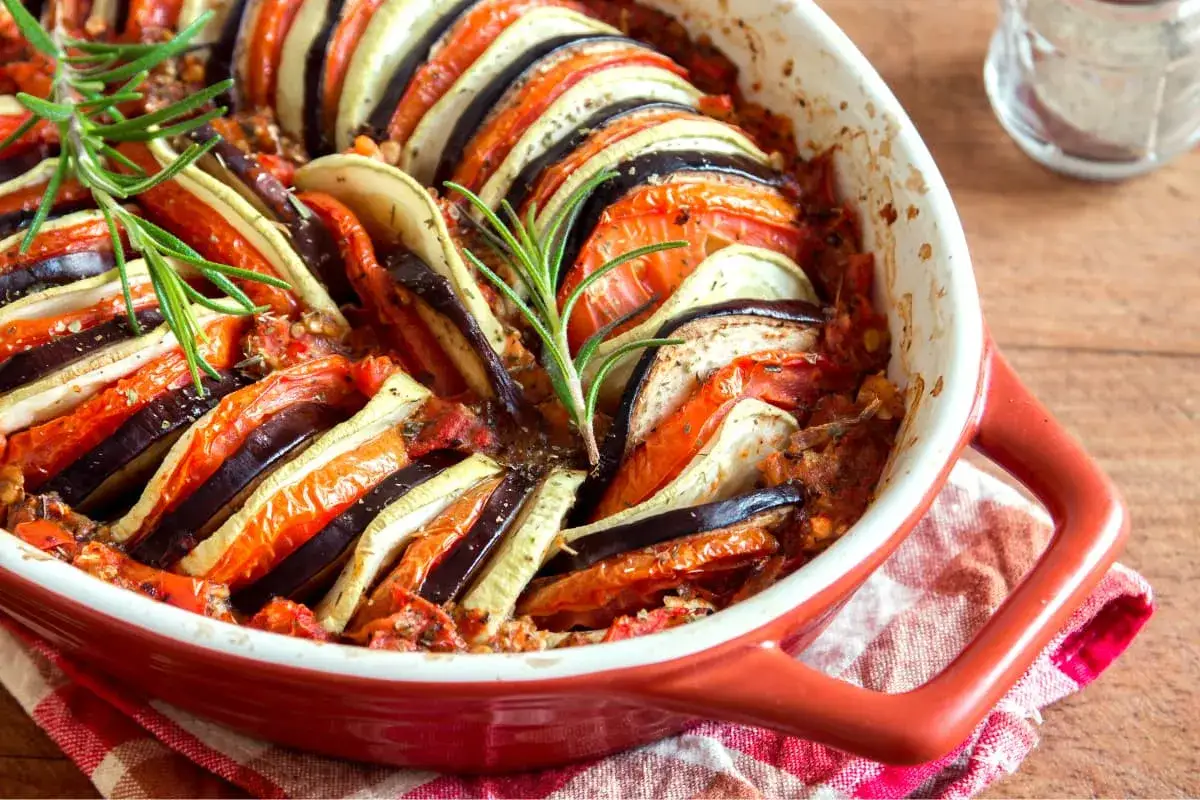 Ratatouille, un dels menjars típics de França, amb rodanxes de carbassó, albergínia i tomàquet cuinades en una safata vermella.