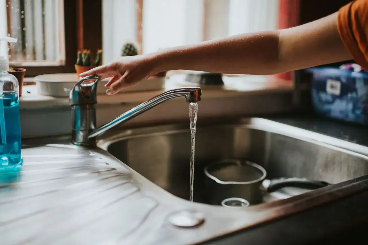Main tenant ouvre le robinet pour remplir une casserole. Il est important de faire bouillir l'eau du robinet avant de la boire pour la purifier.