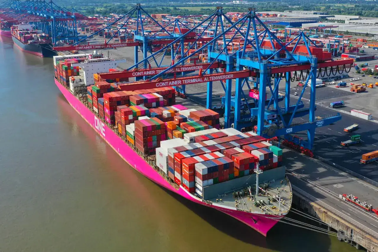 Gro&szlig;es Containerschiff mit vielen bunten Frachtcontainern liegt im Hafen. Kr&auml;ne laden einen weiteren conex container.