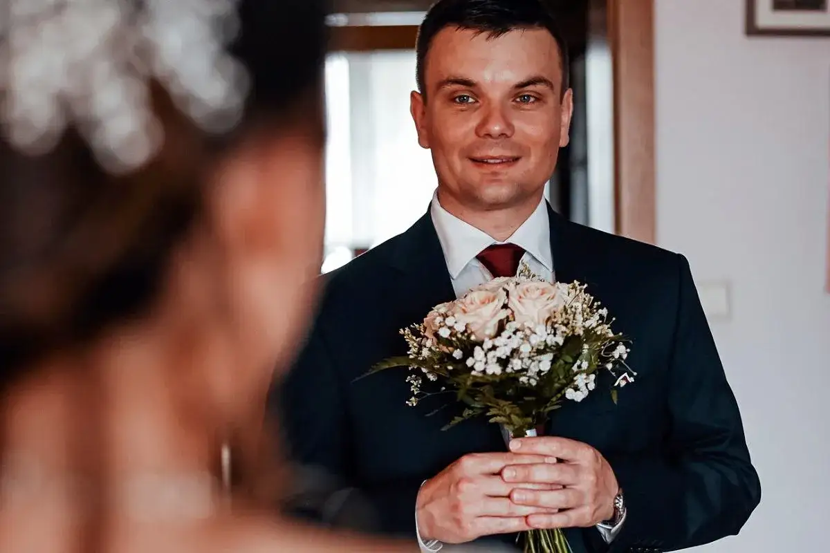 Pan młody z bukietem r&oacute;ż w dłoniach, uśmiecha się do swojej wybranki. Czy były ksiądz może wziąć ślub kościelny? To pytanie, kt&oacute;re nurtuje wiele par.