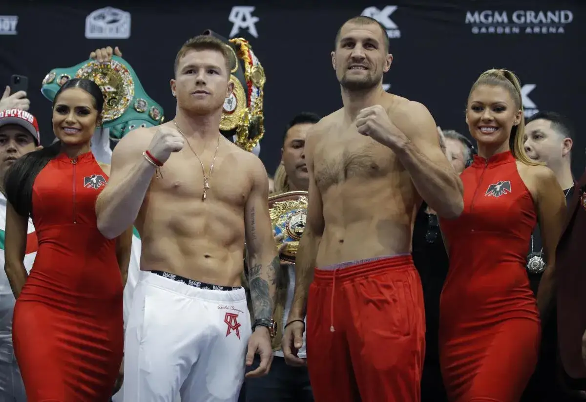 Boxers face off, ready for a junior bantamweight bout. Championship belts gleam behind them.