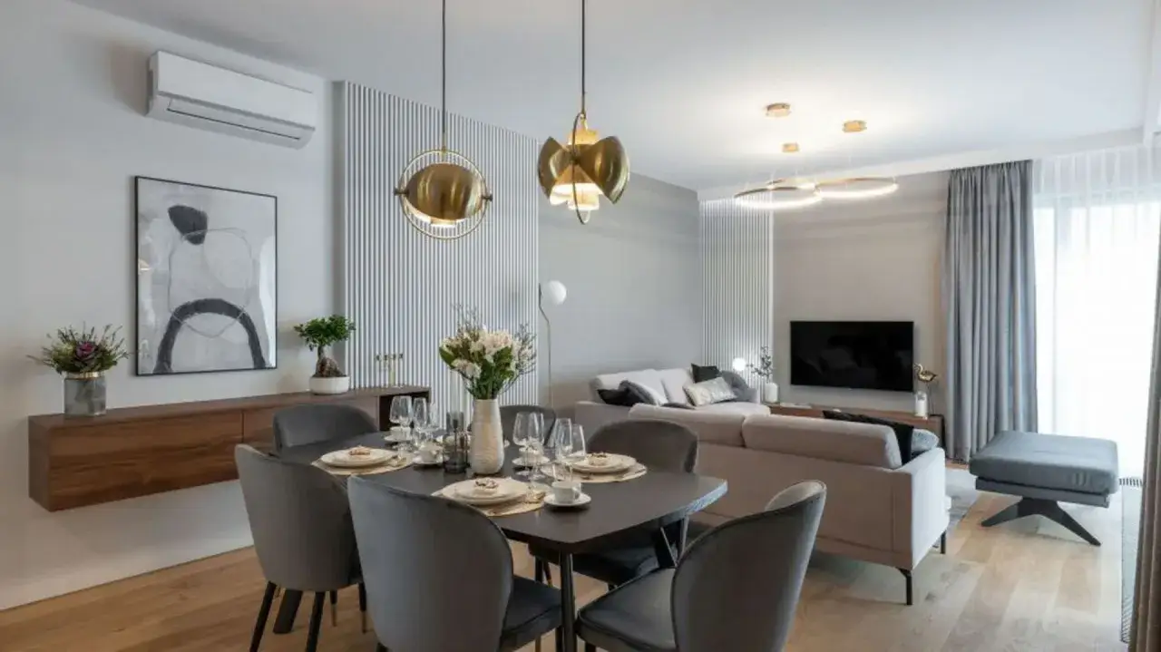 Nowoczesny salon z jadalnią: jak ustawić meble, by stworzyć funkcjonalną i stylową przestrzeń. Elegancka jadalnia z szarymi krzesłami i salon z wygodną kanapą.