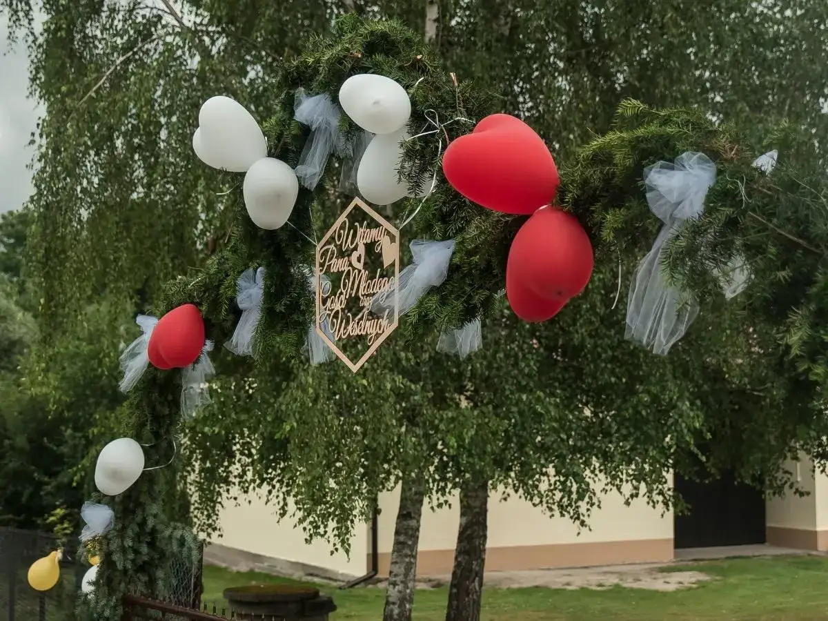 Witajcie Para Młoda! Wesołe wierszyki na wesele dla dzieci za czekoladę ozdabiają gałąź z balonami.