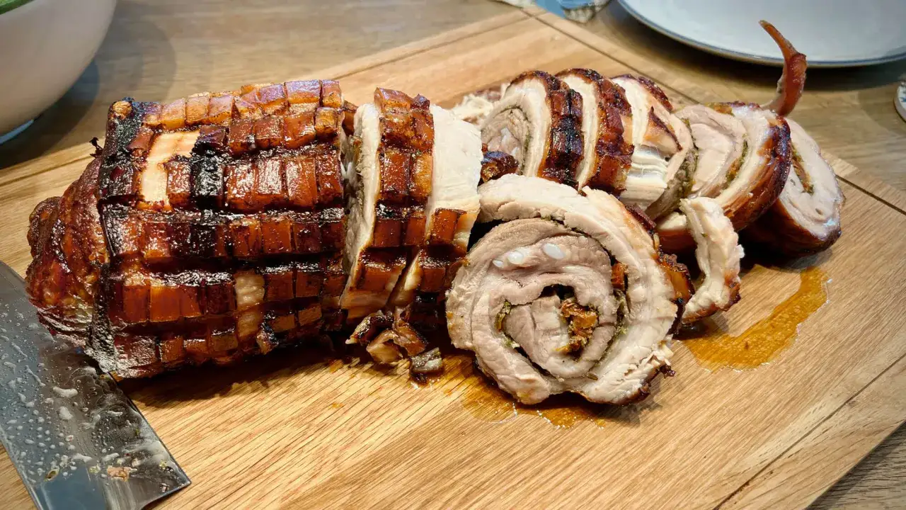 Ein saftiges, gerolltes Schweinefleisch mit knuspriger Schwarte, geschnitten auf einem Holzbrett. Das ist Porchetta, ein italienischer Klassiker!