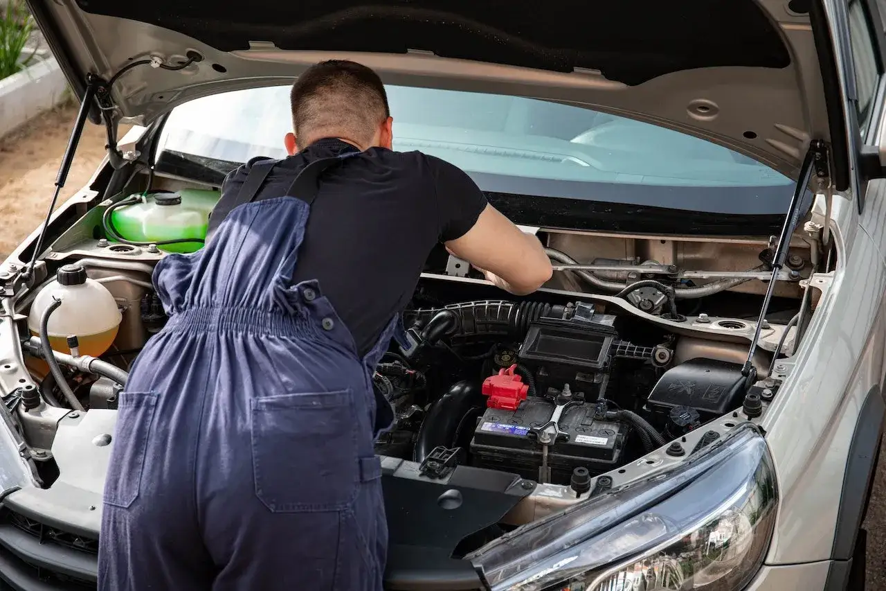 Mechanik w ogrodniczkach sprawdza silnik po płukance, szukając potencjalnych problemów.