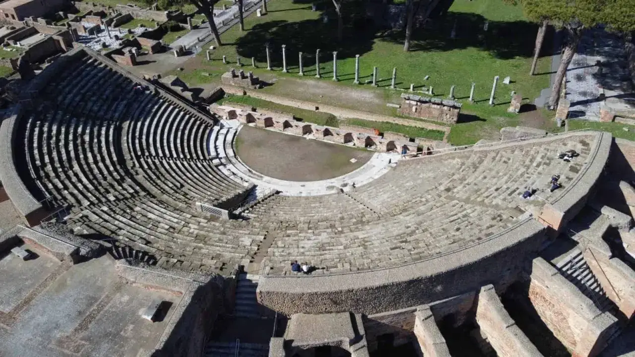 Teatro romano di Ostia Antica, con gradinate in pietra e resti archeologici circostanti.