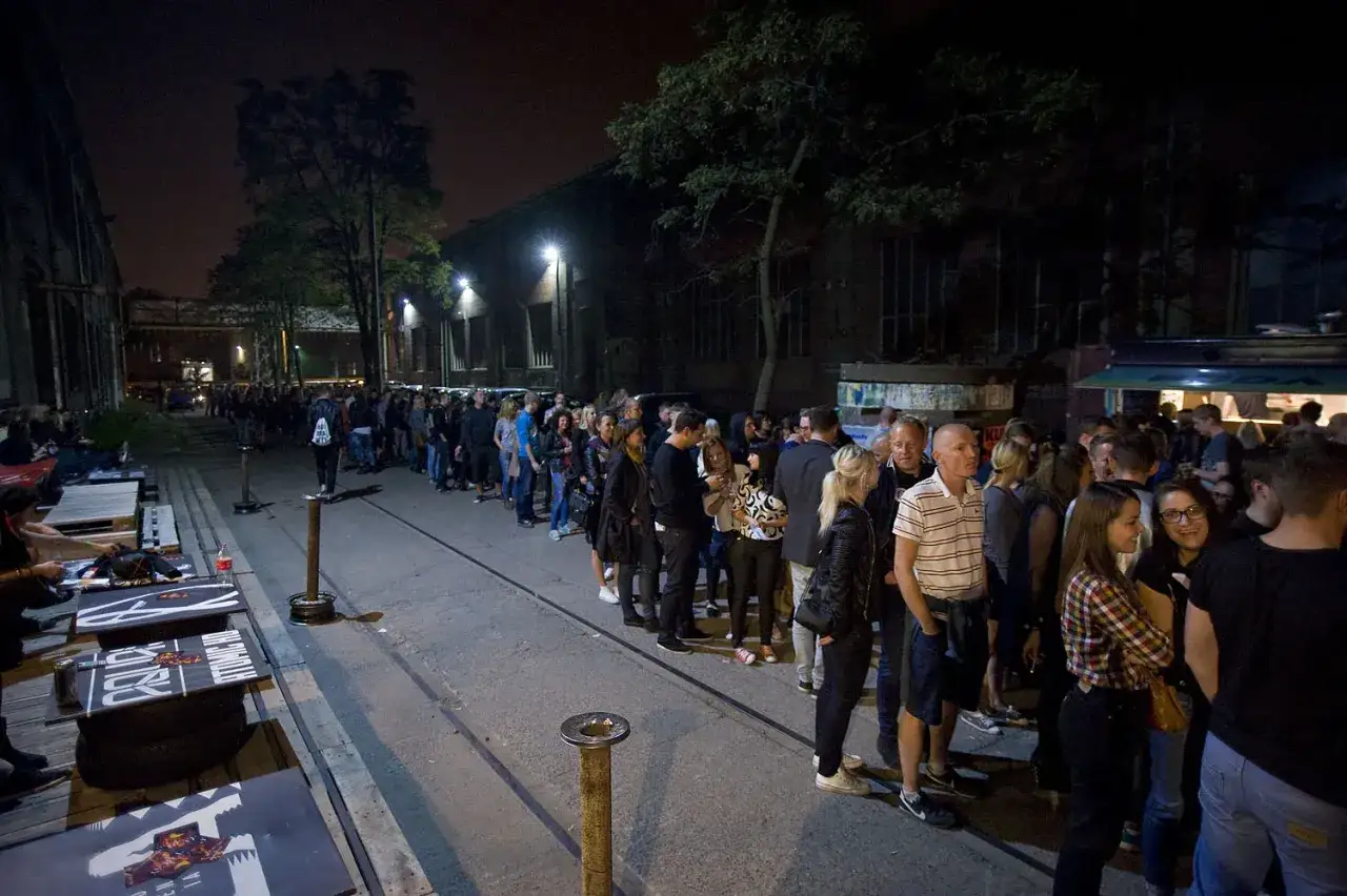 Tłum ludzi czeka w kolejce nocą. Czy to early entrance na wydarzenie?