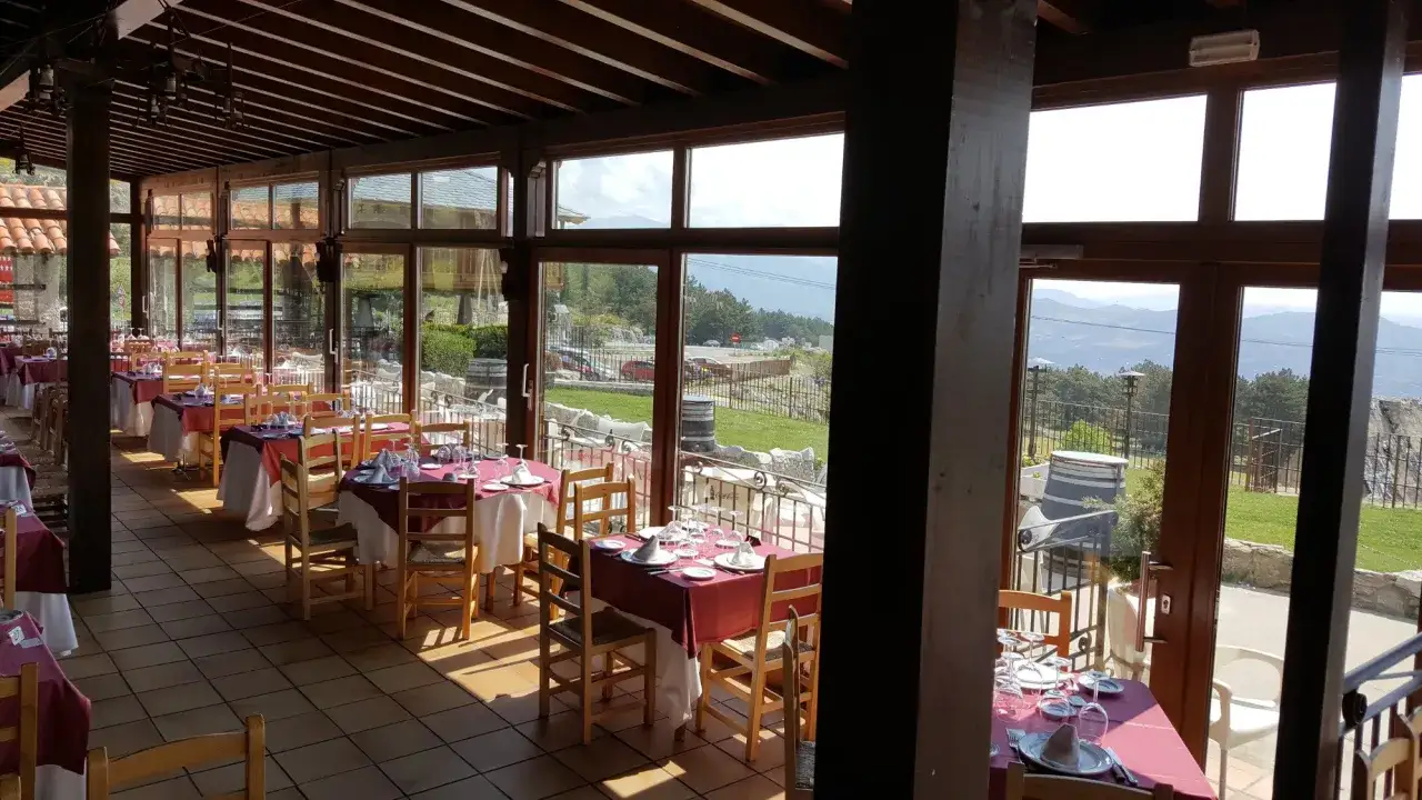 Comedor de restaurantes con zona infantil en la Sierra de Madrid, con mesas preparadas y vistas a la monta&ntilde;a.
