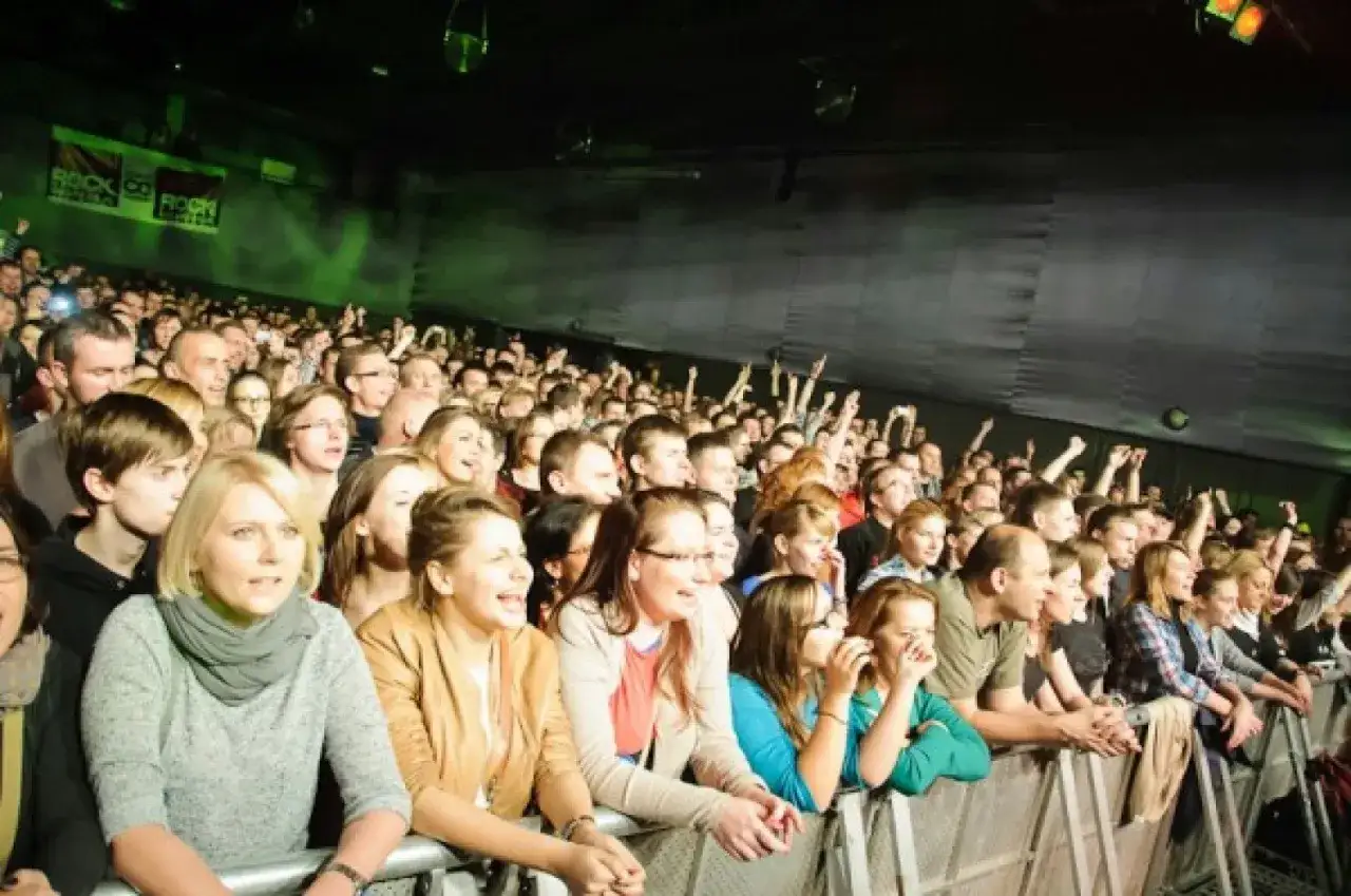 Tłum ludzi na koncercie w klubie Stodoła Warszawa, wszyscy zapatrzeni na scenę, niekt&oacute;rzy klaszczą i podnoszą ręce.