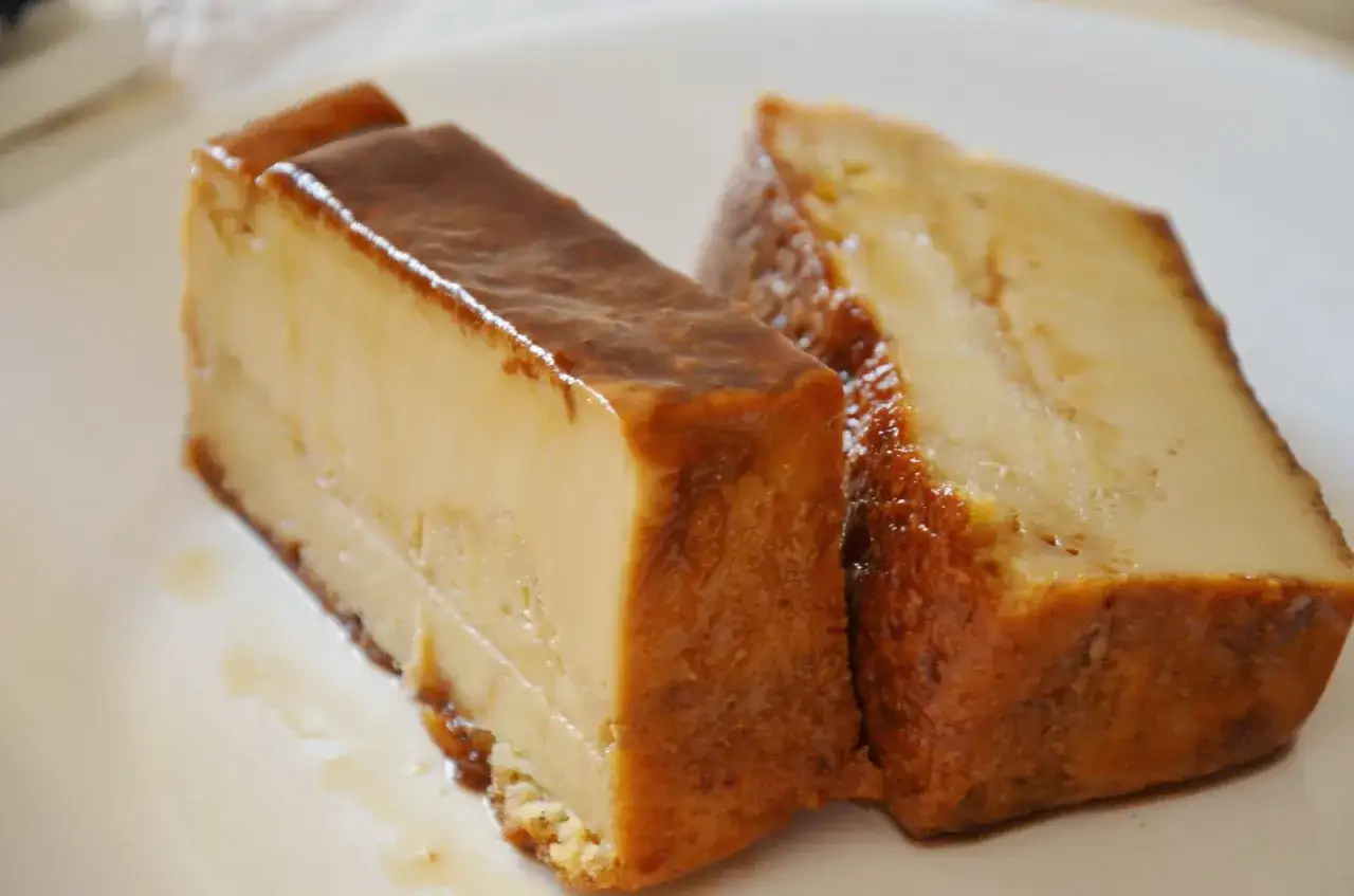 Dos porciones de pan de Calatrava, un postre cremoso con caramelo dorado, servidas en un plato blanco.