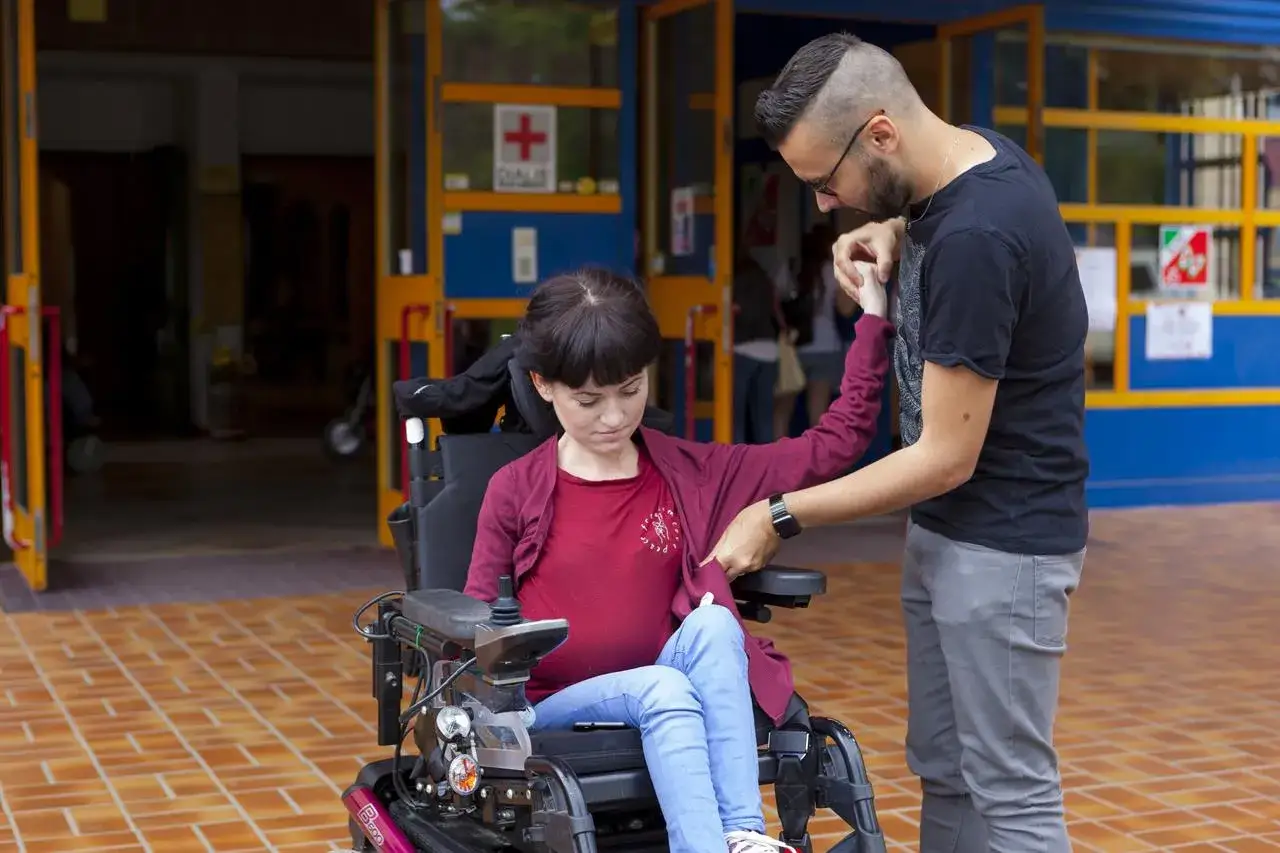 Ragazzo aiuta donna in carrozzina elettrica. Con il 70 per cento di invalidit&agrave; cosa mi spetta? Supporto e dignit&agrave;.