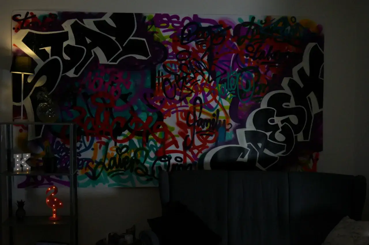 En stor tavla med f&auml;rgstark graffiti. Konstn&auml;ren har valt att m&aring;la graffiti med m&aring;nga olika f&auml;rger och former.