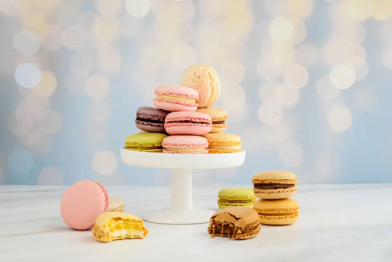 Bunte Macarons, frisch aus dem Ofen, stapeln sich auf einer weißen Tortenplatte. Ein Genuss für Augen und Gaumen beim Macarons backen.