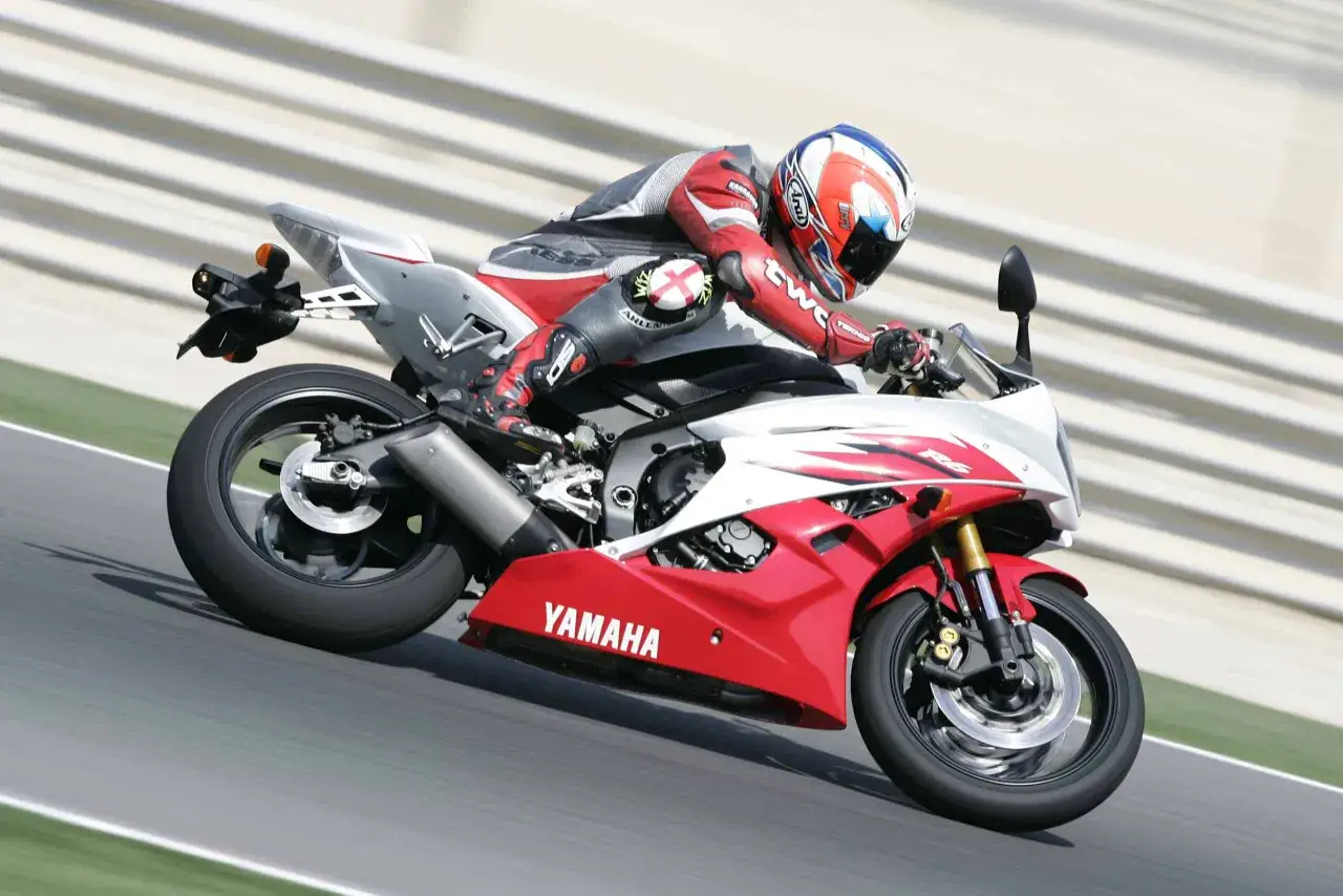 Motocyklista w czerwonym kombinezonie śmiga na torze Yamahą R6. Od ilu lat można robić prawo jazdy na motor 600? Od 20.