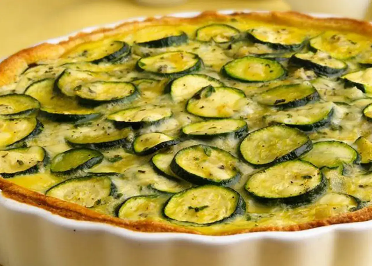 Torta salata zucchine e ricotta, con fette di zucchine dorate e un ripieno cremoso, pronta per essere gustata.