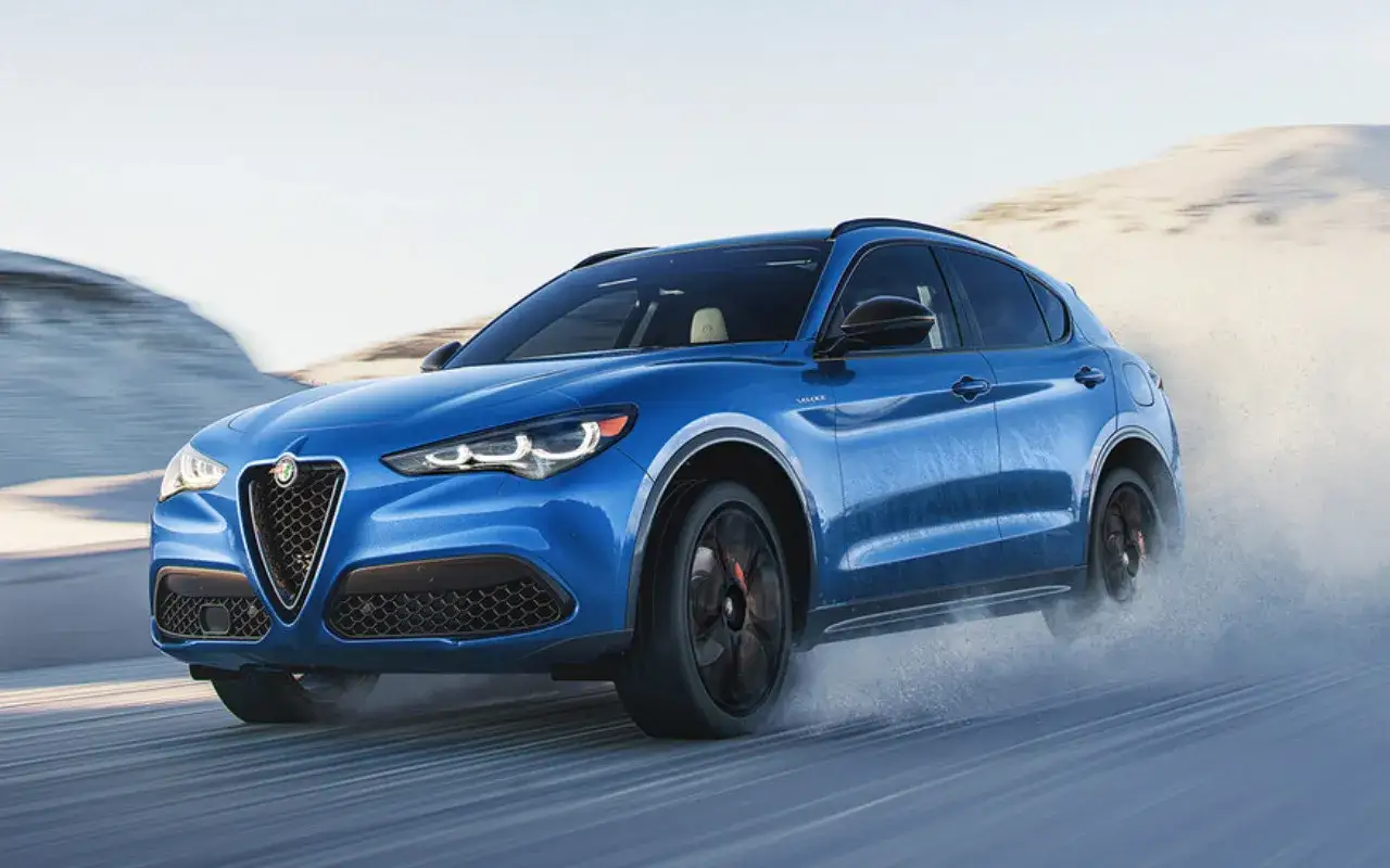 Niebieskie Alfa Romeo Stelvio w ruchu, rozpryskujące wodę. Poznaj jego imponujące alfa romeo stelvio wymiary.