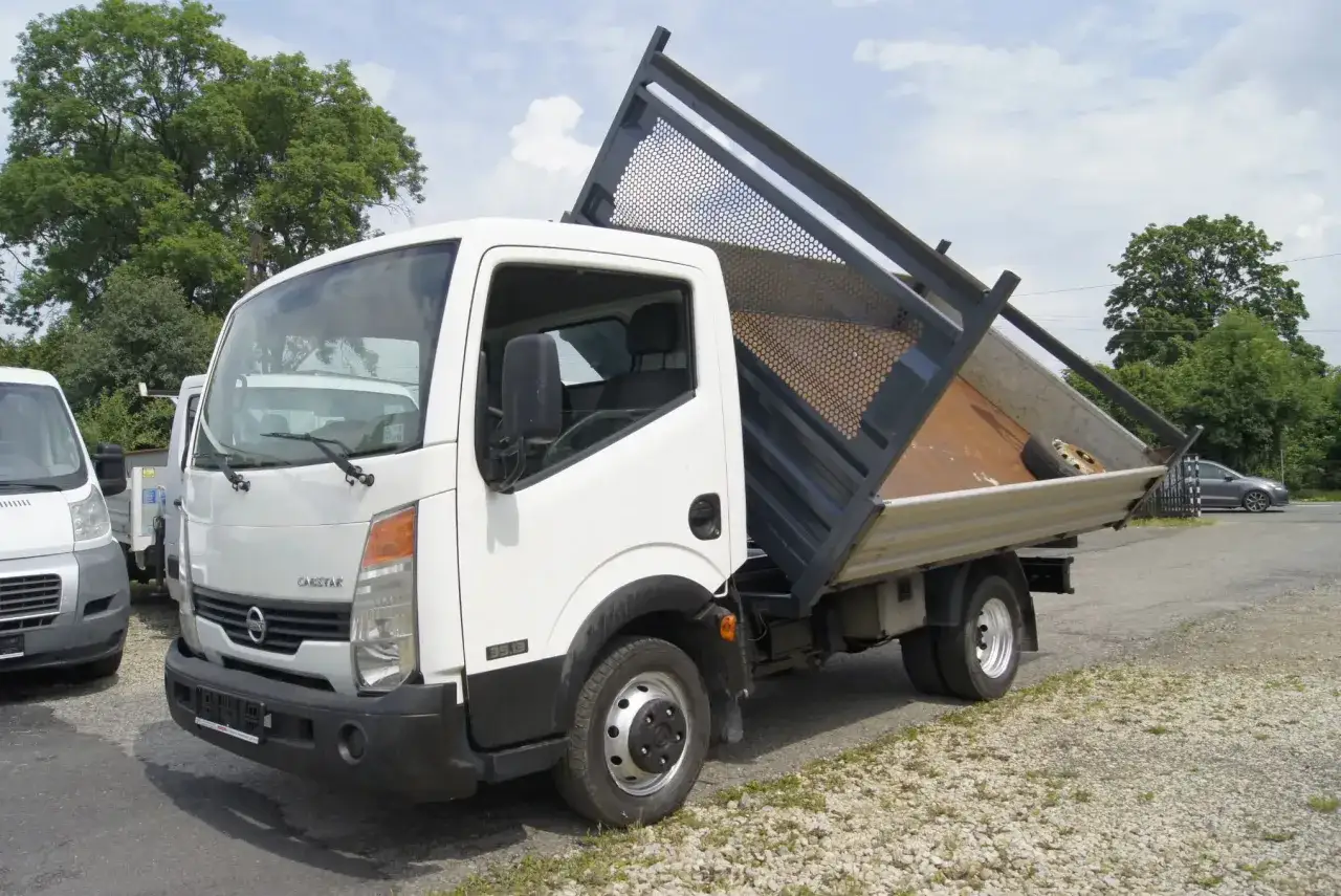 Biały Nissan Cabstar z podniesioną skrzynią ładunkową, gotowy do pracy.
