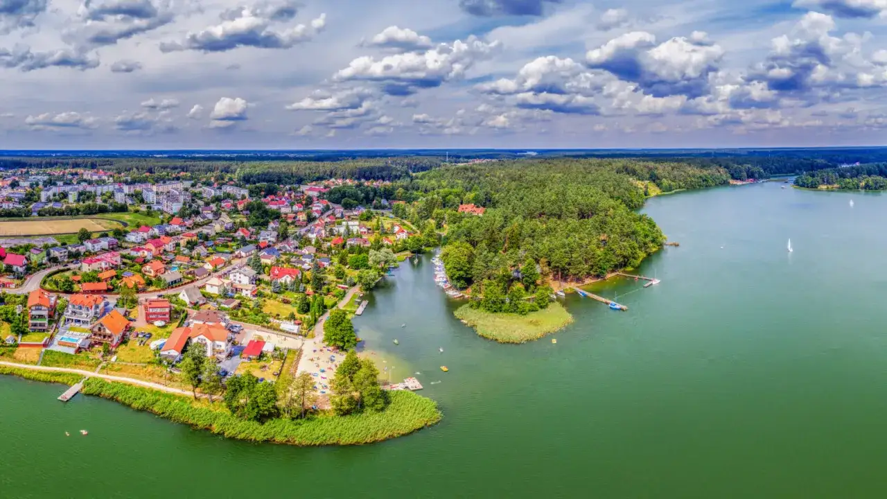 Malownicze Ruciane-Nida z lotu ptaka. Jezioro, lasy i urokliwe domy tworzą idealne miejsce na rodzinne wakacje. Mn&oacute;stwo atrakcji dla dzieci czeka nad wodą!