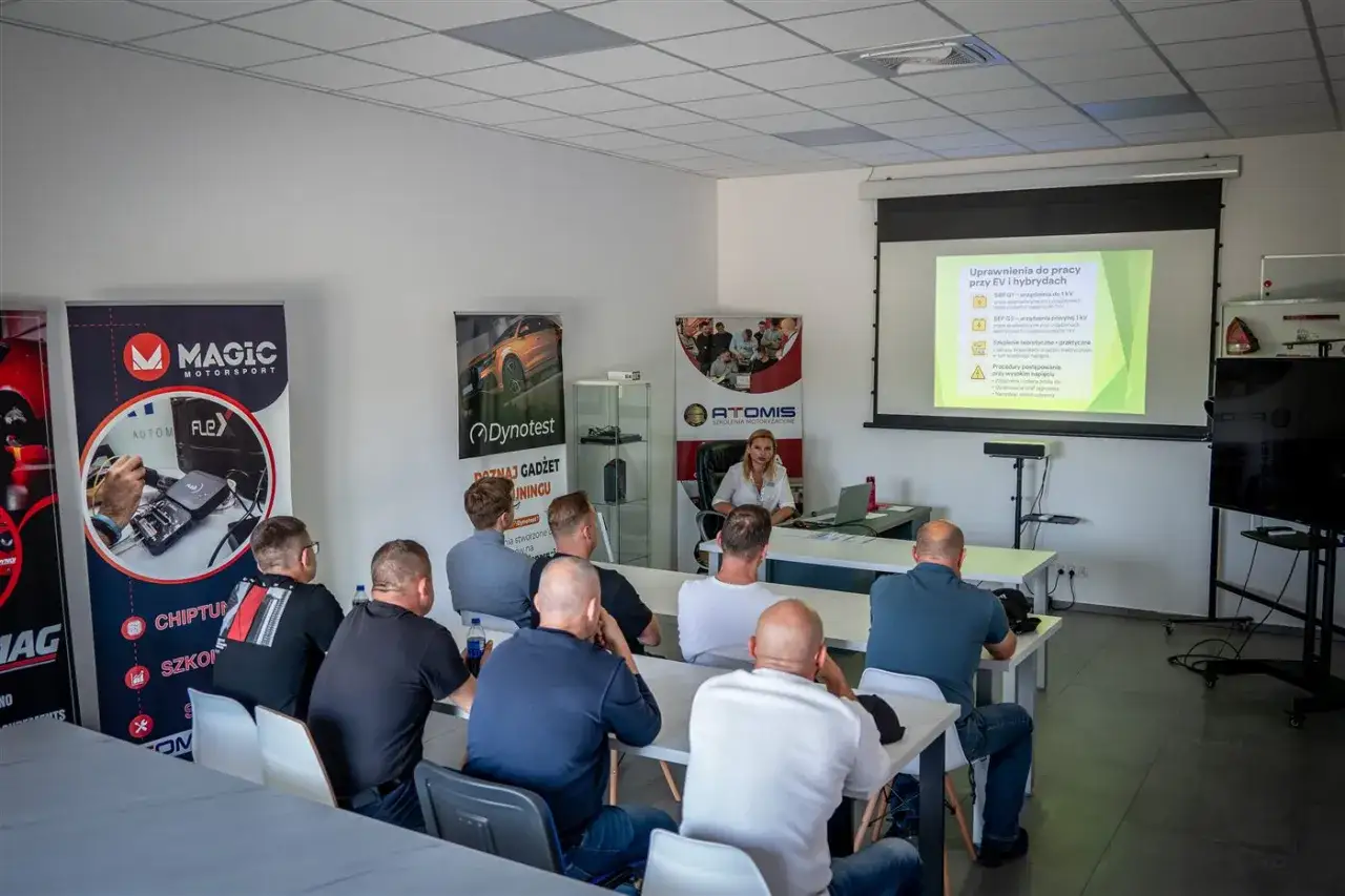 Szkolenie z uprawnień SEP do 1kV dla mechaników samochodowych. Uczestnicy słuchają wykładu o pracy przy pojazdach elektrycznych i hybrydowych.
