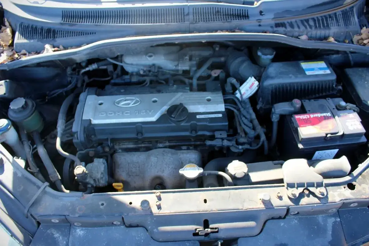 Silnik Hyundai Getz 1.1 DOHC 16V, akumulator i inne elementy komory silnika.
