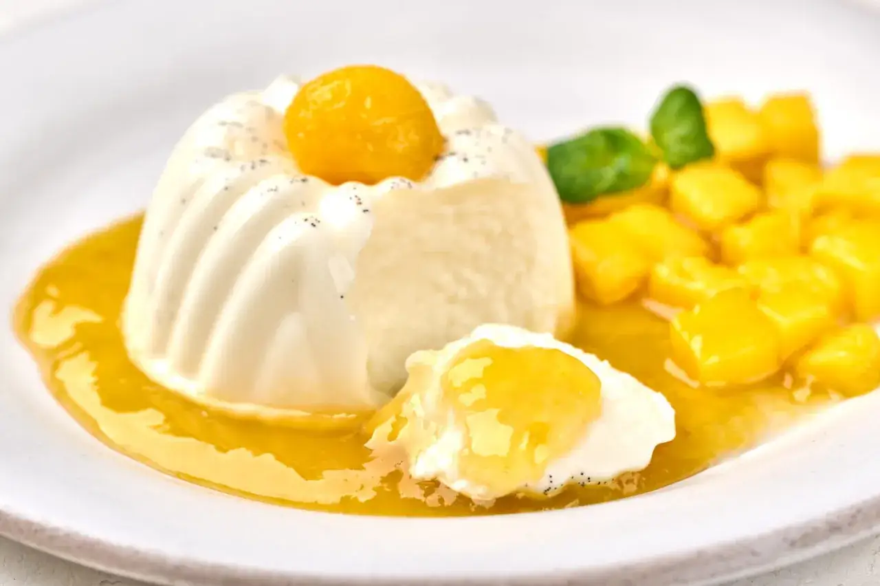 Blanc manger coco recette : un dessert crémeux et onctueux, garni d'une sphère jaune et de dés de mangue, nappé d'un coulis fruité.
